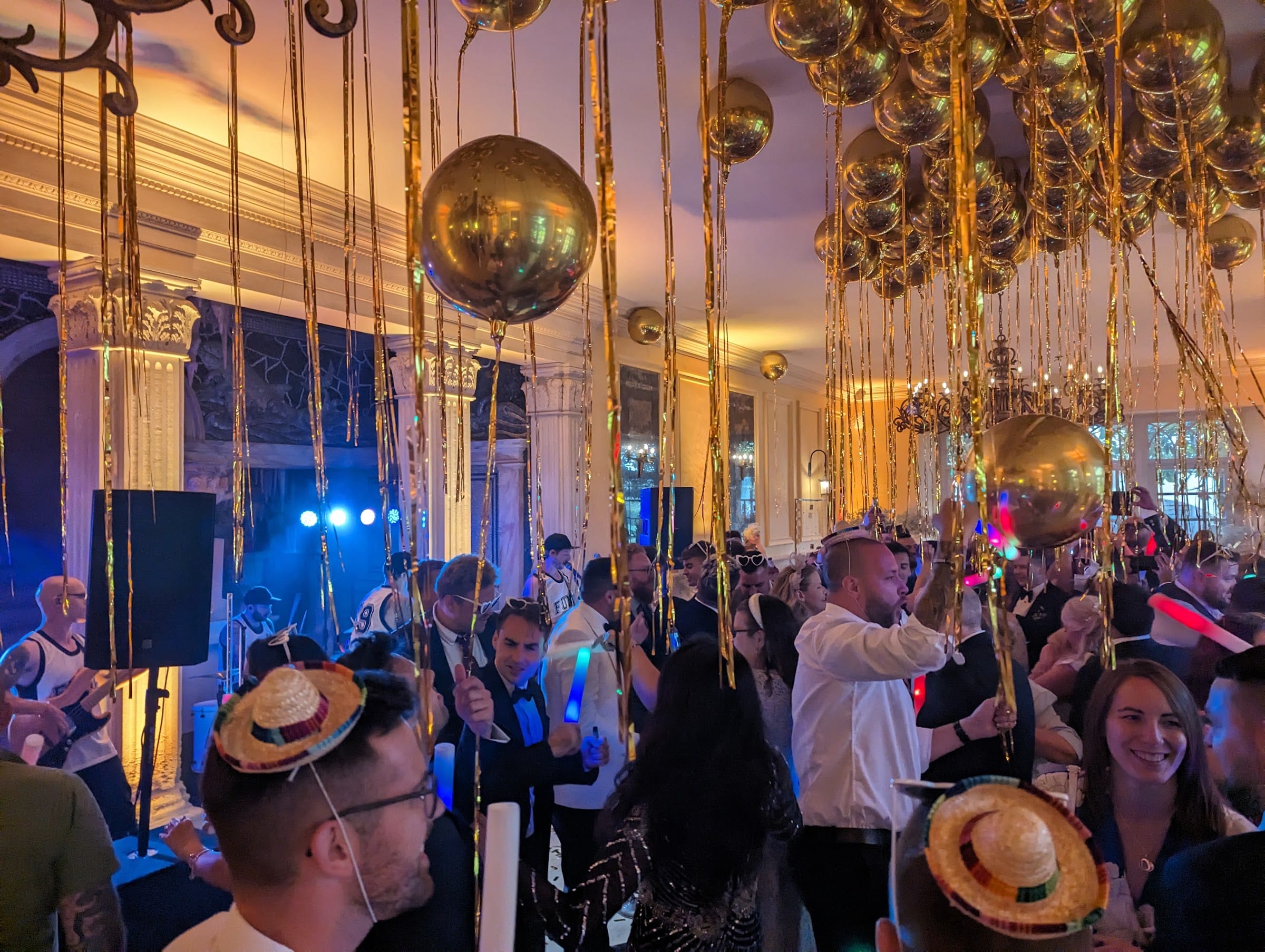 Guests dancing in a ballroom hung with mirror balls and streamers