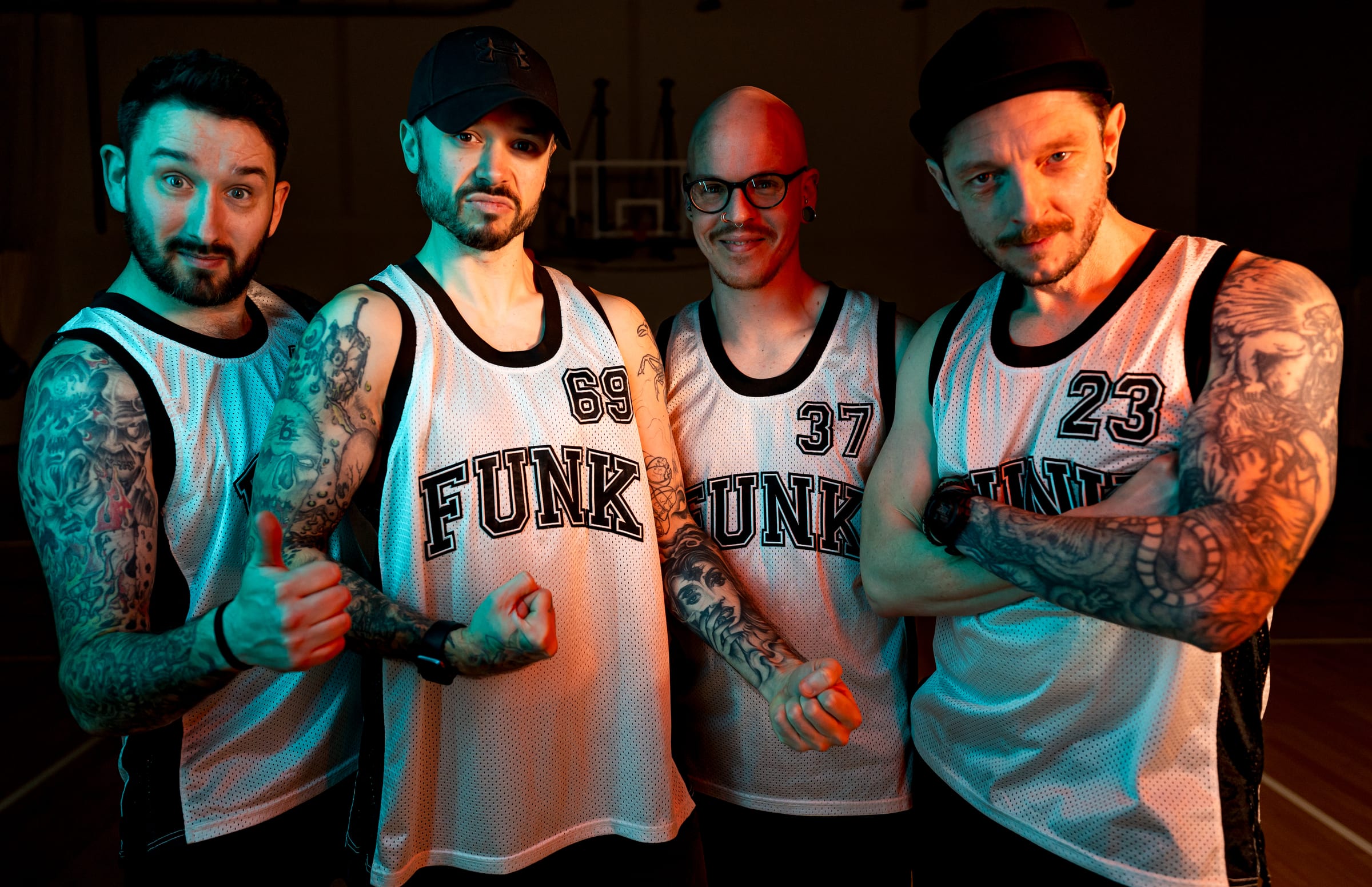 The four of them in FUNK basketball vests, lit teal and orange in a sports hall