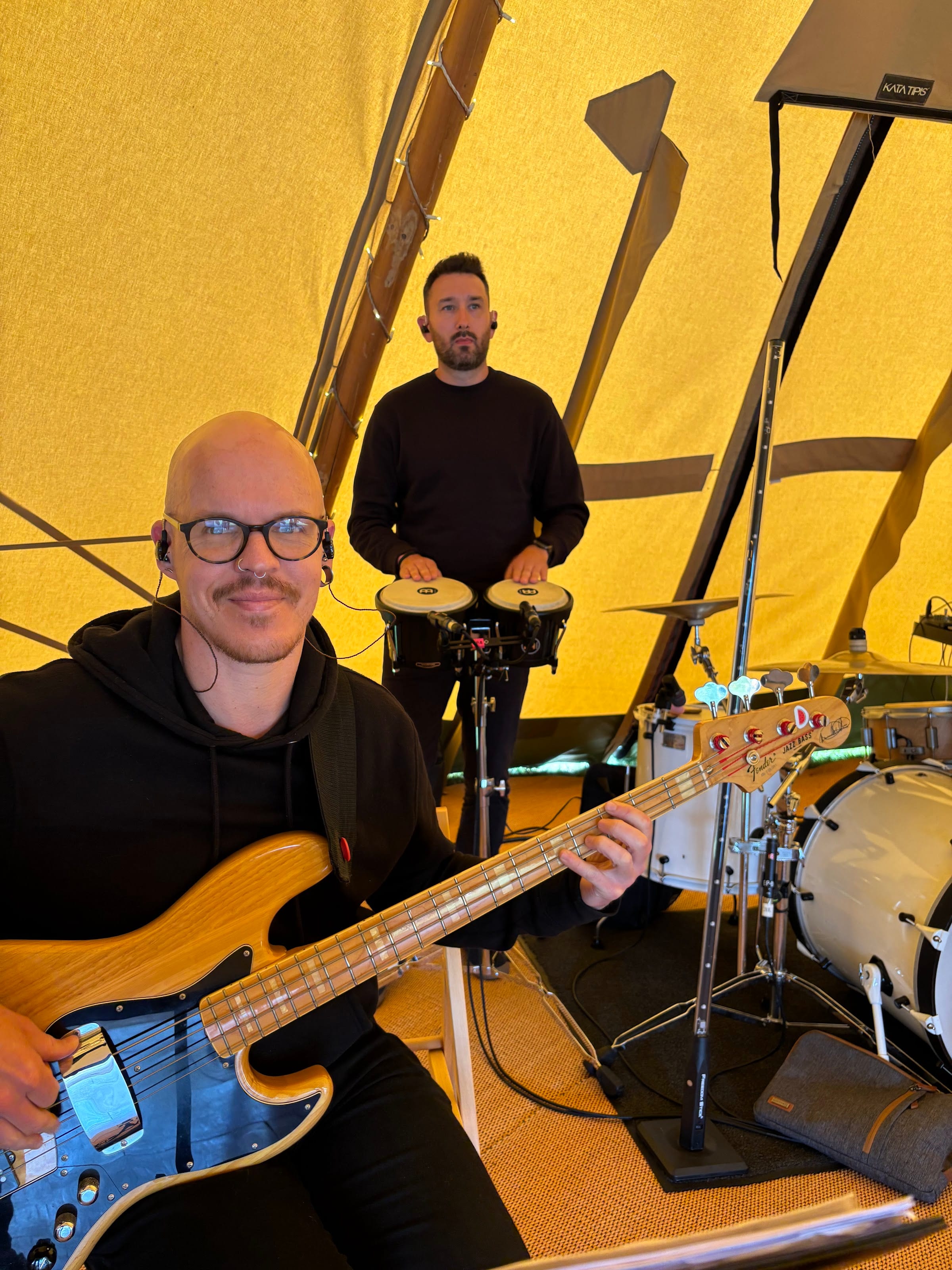 The bass player grinning behind his bass in a tipi