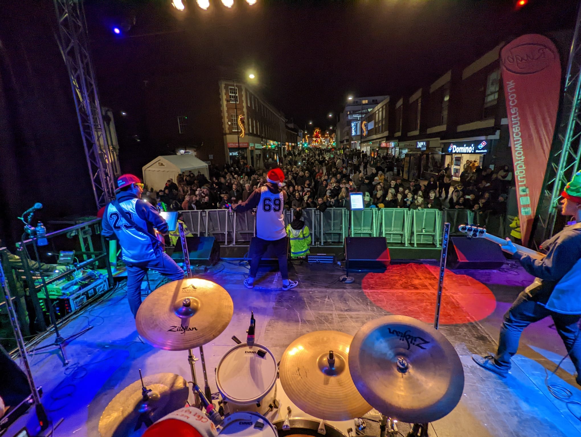 The band playing an outdoor street stage to a large crowd